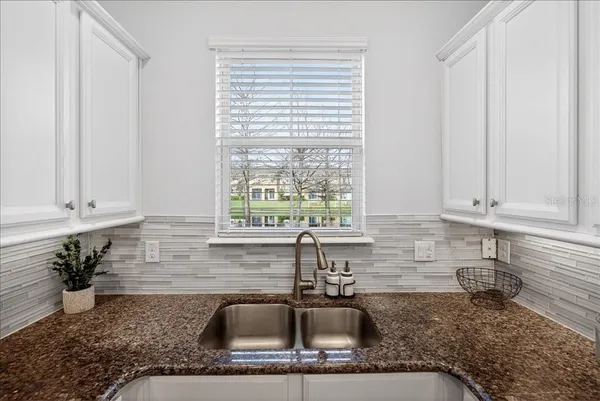a kitchen with granite countertop a sink a stove and cabinets