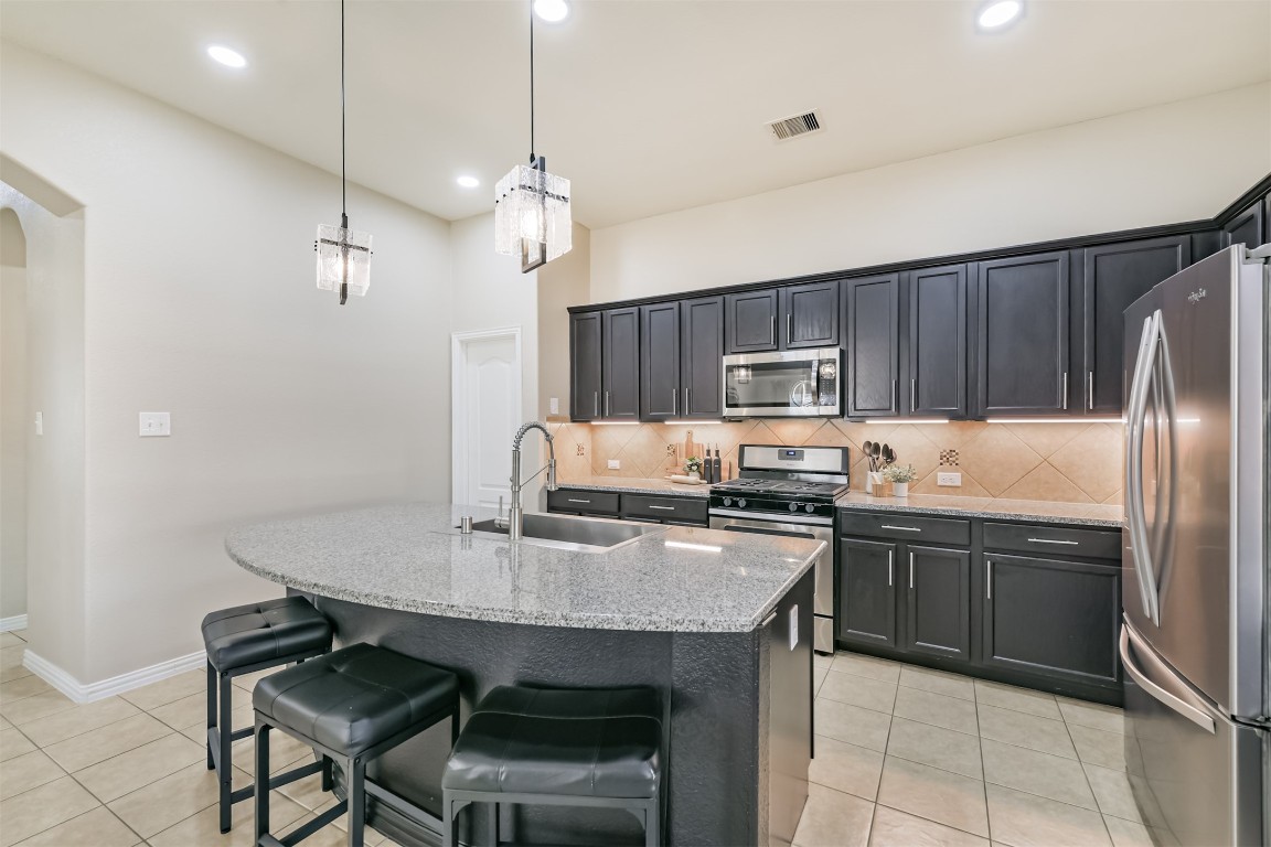 9622 Invergarry Way Tomball, TX 77375 - Photo 9 of 32 a kitchen with kitchen island granite countertop a table chairs stainless steel appliances and cabinets