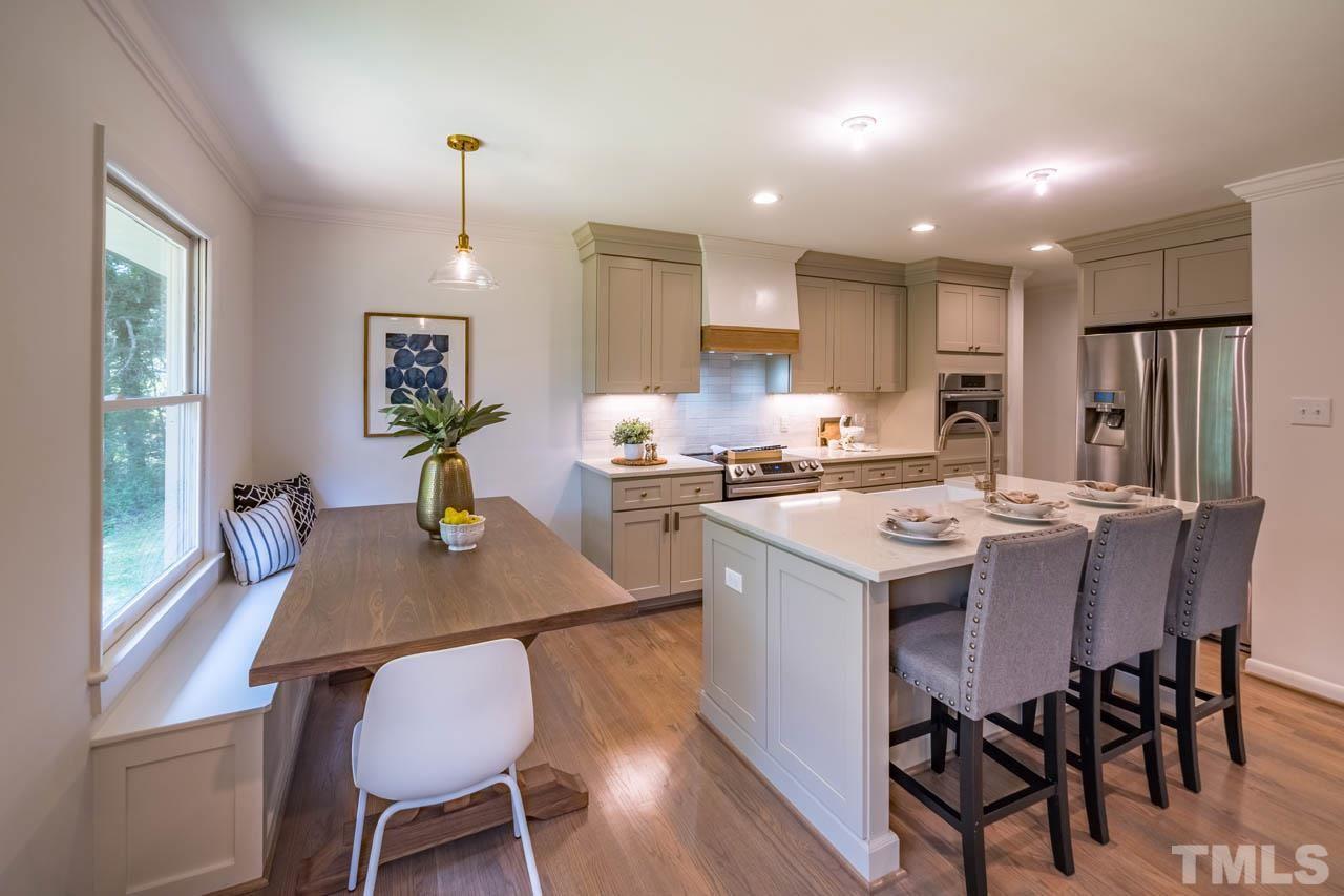 2823 Ridge Road Durham, NC 27705 - Photo 8 of 30 a kitchen with a table chairs a sink dishwasher stove and cabinets with wooden floor