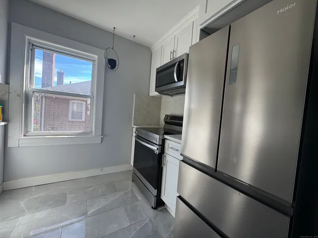 a view of a refrigerator in kitchen and an empty room