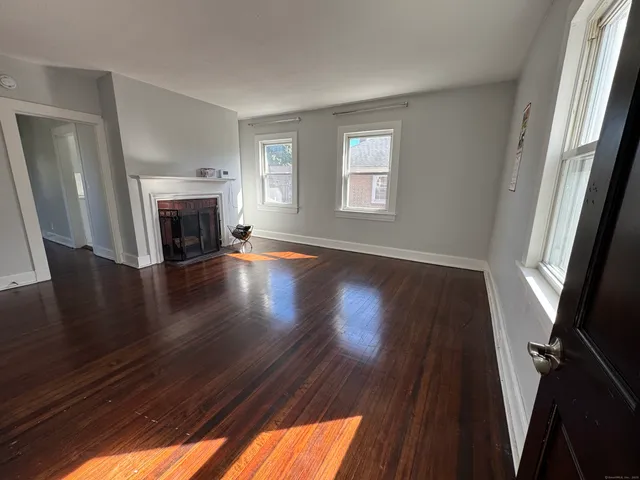 a view of a livingroom with wooden floor and a fireplace