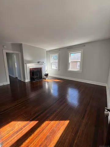 a view of empty room with wooden floor and fireplace