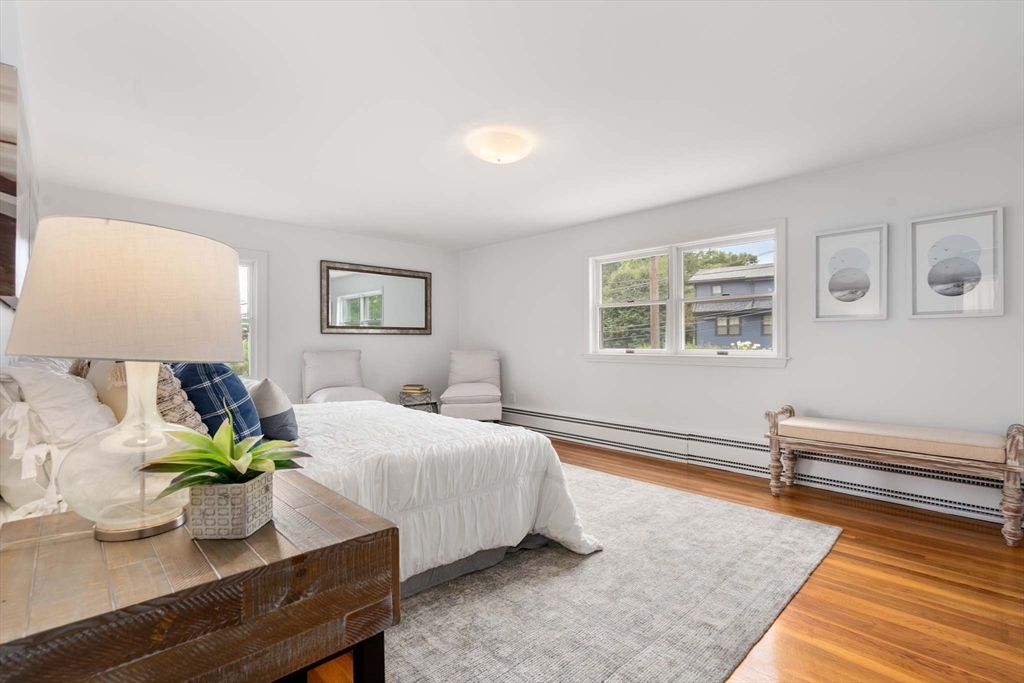 226 Grove Street Brookline, MA 02467 - Photo 11 of 23 a bedroom with a bed potted plant on dresser and a wooden floor
