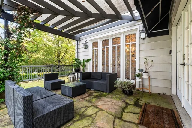 a view of a white house with a large tree and wooden fence