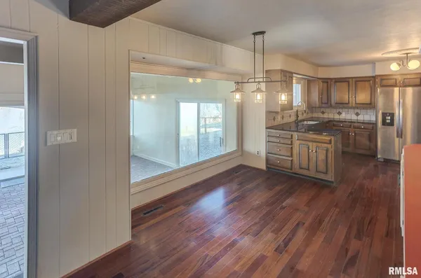 a kitchen with stainless steel appliances granite countertop a refrigerator a sink dishwasher a stove and white countertops with wooden floor