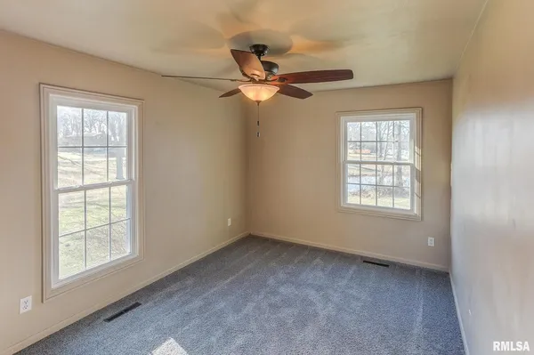 an empty room with a window and a fan