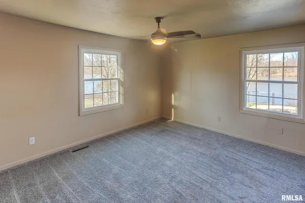 an empty room with windows and fan