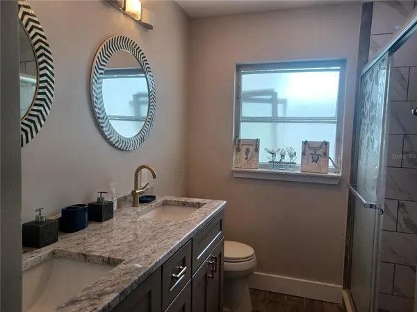 a bathroom with a granite countertop toilet a sink and a mirror
