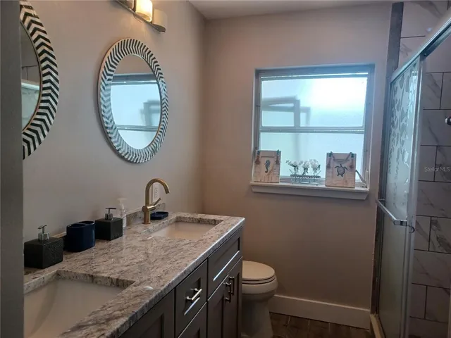 a bathroom with a granite countertop toilet a sink and a mirror