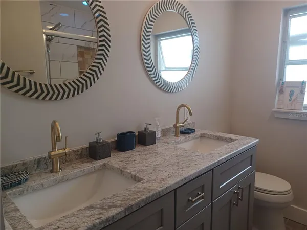 a bathroom with a granite countertop double vanity sink and a mirror