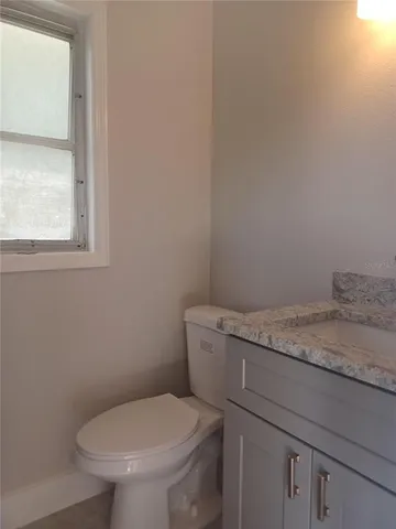 a bathroom with a granite countertop toilet and a sink