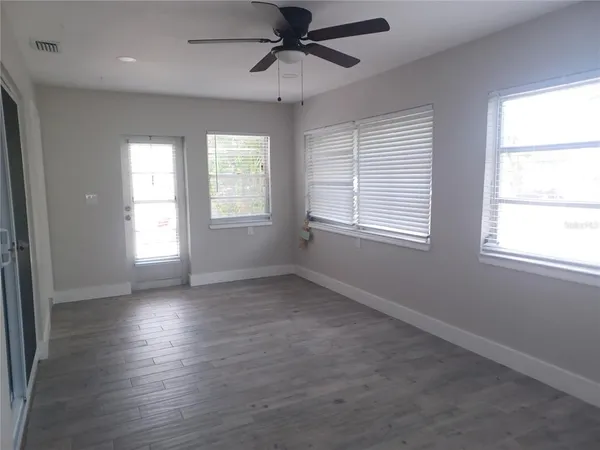 a view of an empty room with wooden floor and a window