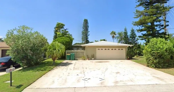 a view of a white house with a yard and large trees