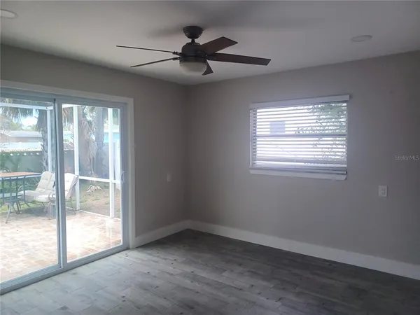 a view of empty room with wooden floor and fan