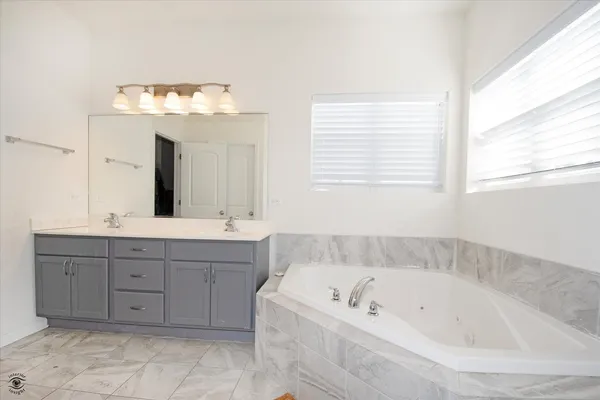 a bathroom with a tub a sink and a window