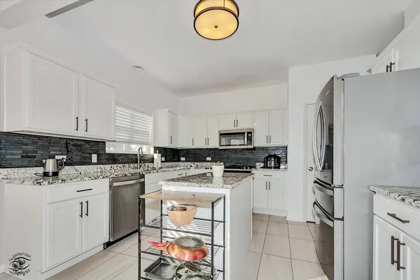 a kitchen with a refrigerator a stove top oven a sink dishwasher and white cabinets with wooden floor