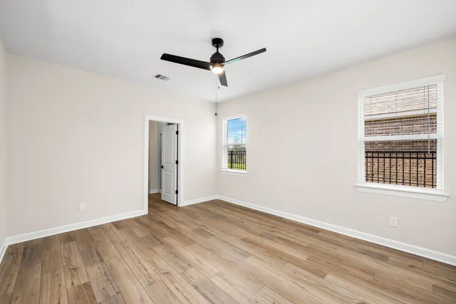 a view of empty room with wooden floor and fan
