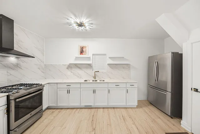 a kitchen with granite countertop a stove a sink and a refrigerator