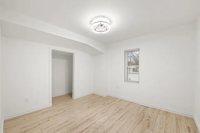 an empty room with wooden floor and a ceiling fan