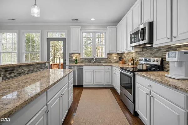 a kitchen with stainless steel appliances granite countertop a sink a stove top oven a counter space and cabinets