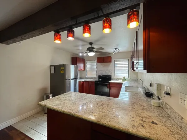a kitchen with stainless steel appliances kitchen island granite countertop a table chairs in it and wooden floor