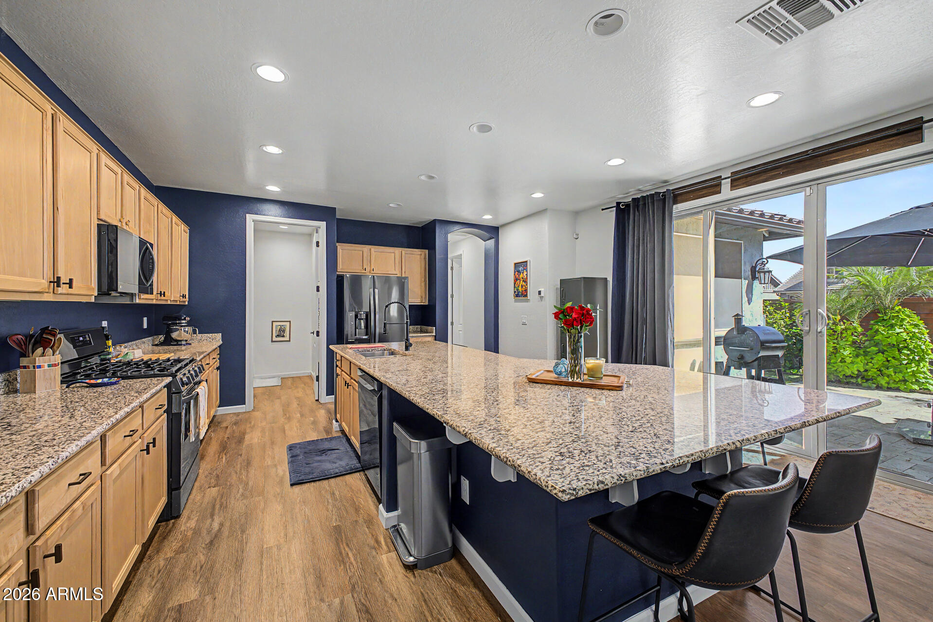 3940 East Turley Street Gilbert, AZ 85295 - Photo 13 of 50 a kitchen with granite countertop kitchen island stainless steel appliances a stove a sink a refrigerator and a dining table with wooden floor