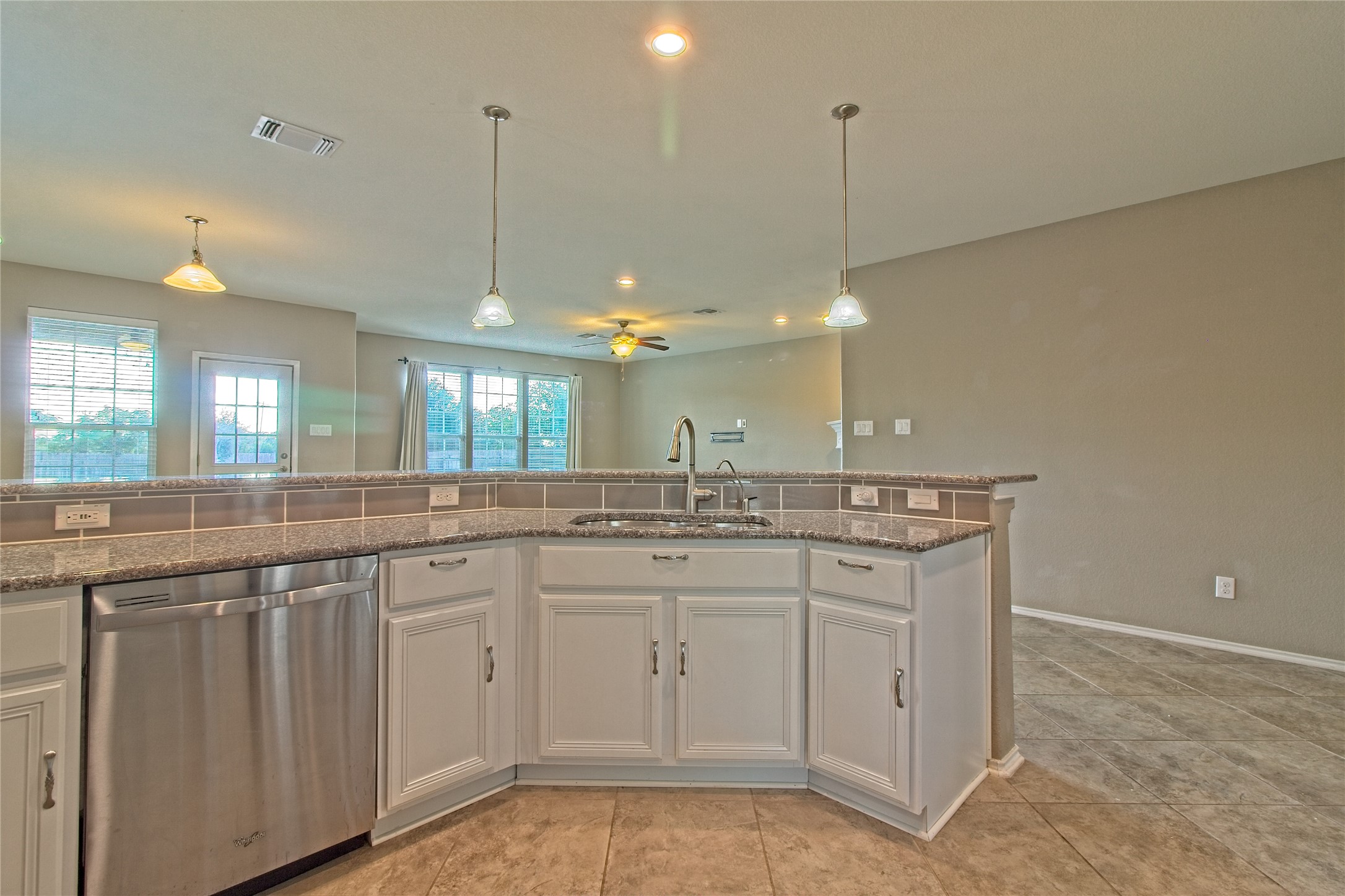 31443 Kingsway Road Georgetown, TX 78628 - Photo 14 of 40 A corner kitchen island anchors an open-concept living space with granite counters and tile flooring.