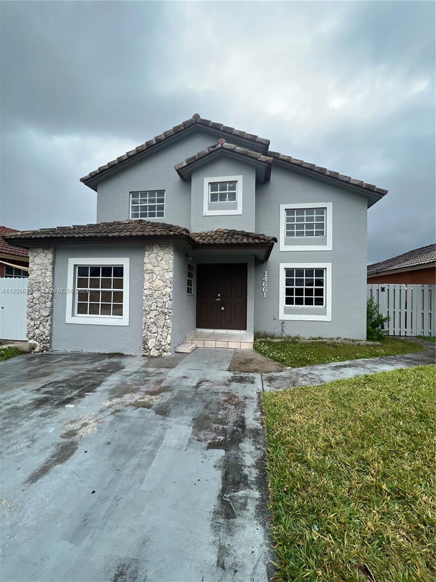 a front view of a house with a garden and yard