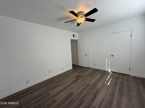an empty room with wooden floor and a ceiling fan