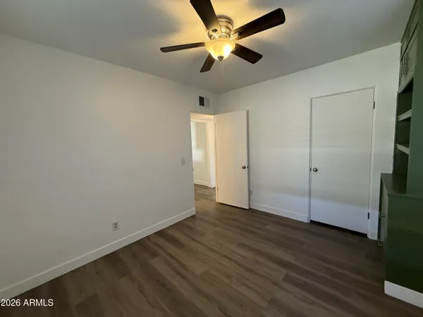 an empty room with wooden floor and fan