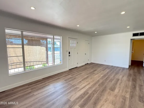 a view of empty room with wooden floor and fan