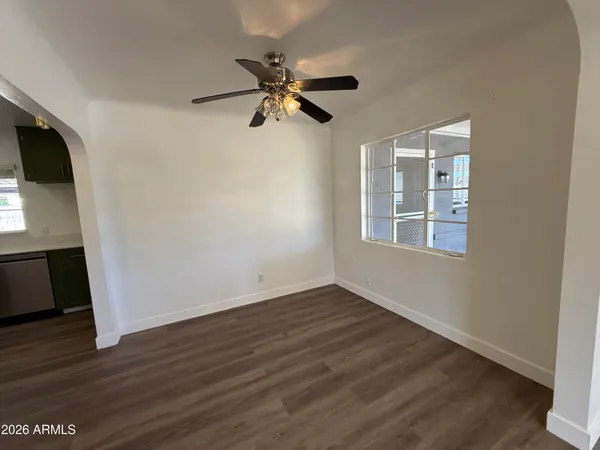 a view of empty room with wooden floor and fan