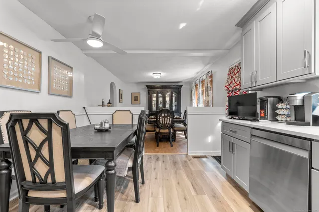 a open kitchen with stainless steel appliances granite countertop a stove a refrigerator a sink a dining table and chairs with wooden floor