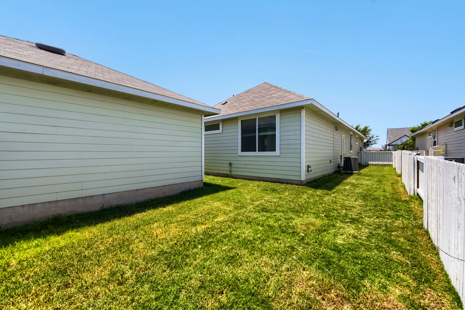 1310 Goforth Road Kyle, TX 78640 - Photo 22 of 24 Fenced backyard featuring a manicured lawn, horizontal siding, single-hung windows, and a shingle roof