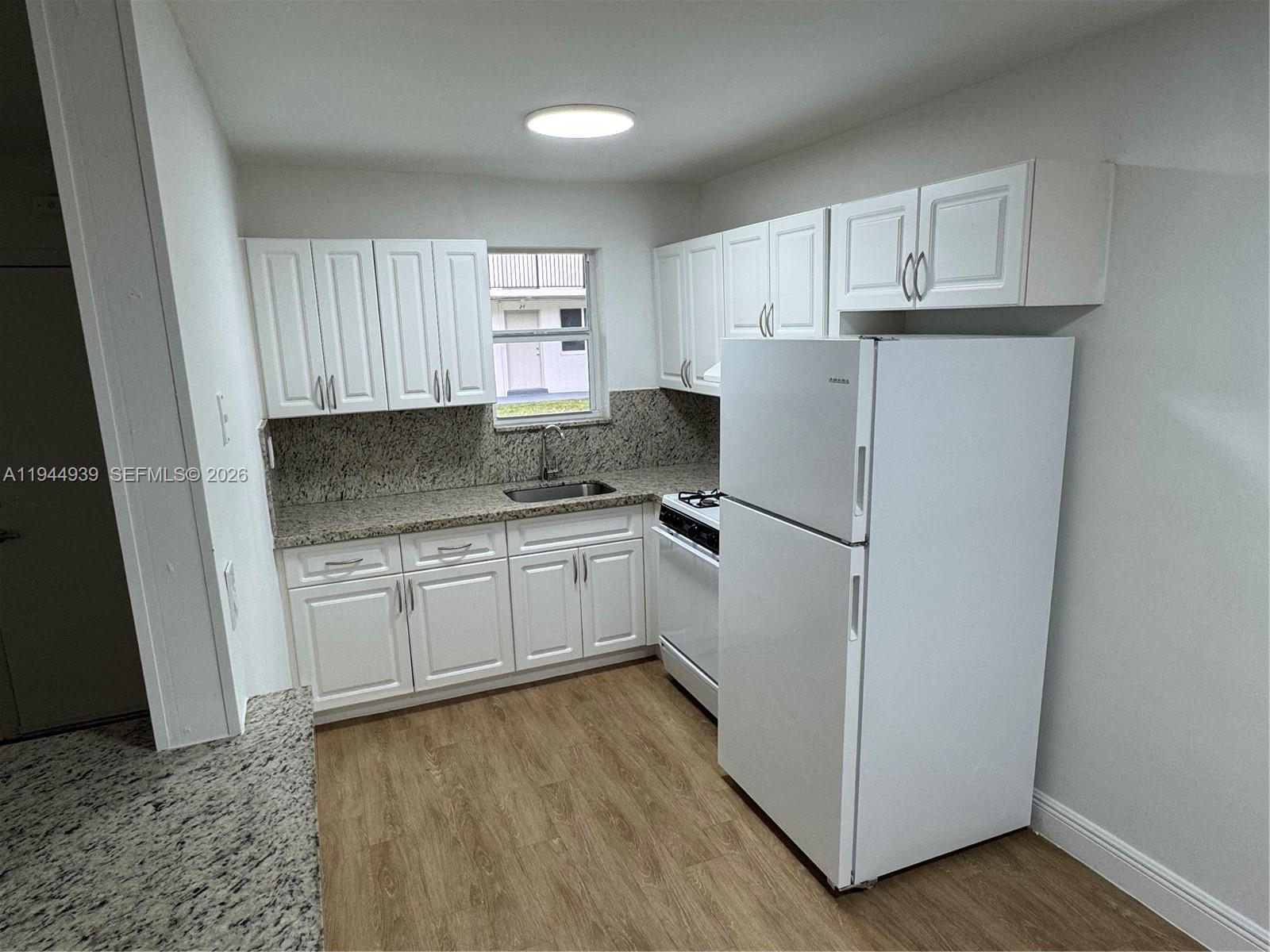 6775 Southwest 44th Street, Unit 20 Miami, FL 33155 - Photo 3 of 6 a kitchen with granite countertop a refrigerator sink and cabinets