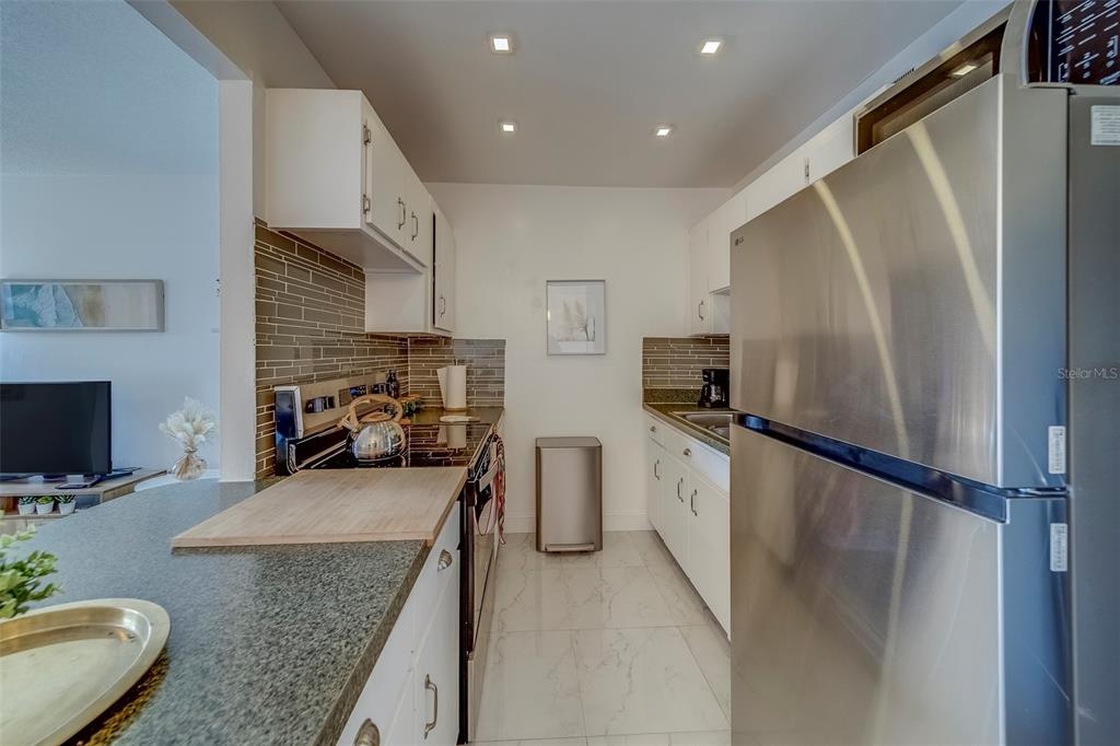 361 South McMullen Booth Road, Unit 112 Clearwater, FL 33759 - Photo 14 of 36 a kitchen with stainless steel appliances granite countertop a refrigerator a stove top oven a sink and dishwasher
