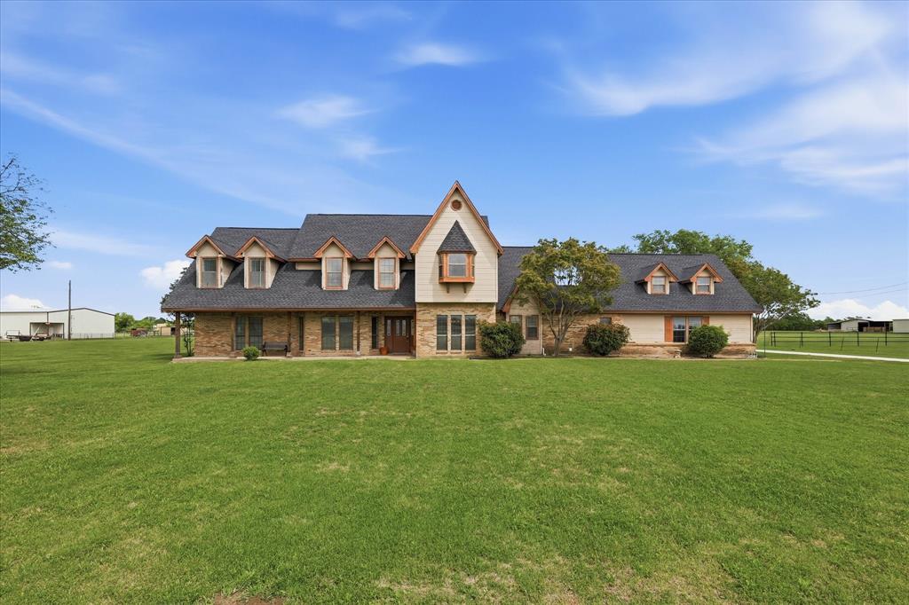 a view of a big house with a big yard and large trees