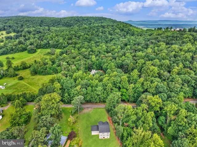 a view of a house with a big yard and large trees
