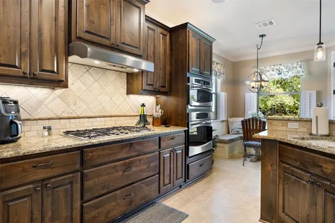 a kitchen with granite countertop wooden cabinets and a stove top oven