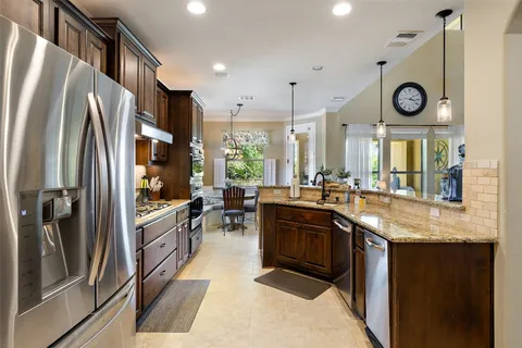 a kitchen with stainless steel appliances granite countertop a sink a stove top oven a refrigerator with island and chairs