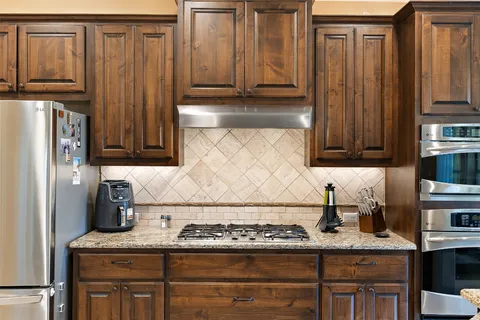a kitchen with stainless steel appliances granite countertop wooden cabinets and a counter top space
