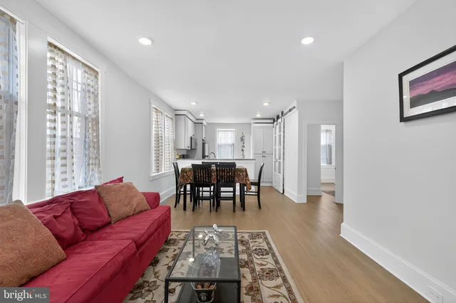 a living room with furniture and a dining table with wooden floor