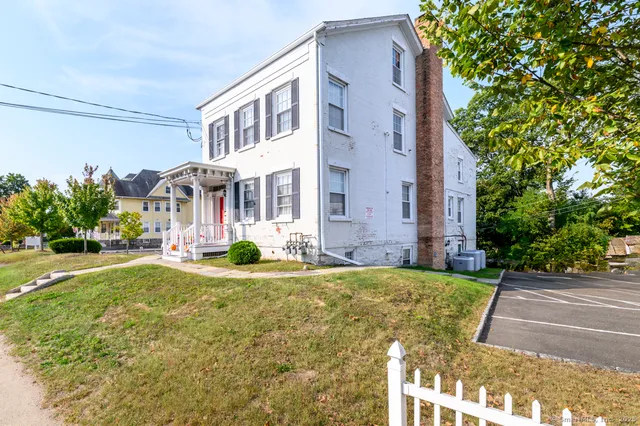 a front view of multi story residential apartment building with yard and parking