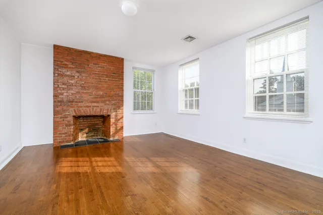 a view of empty room with wooden floor and fireplace