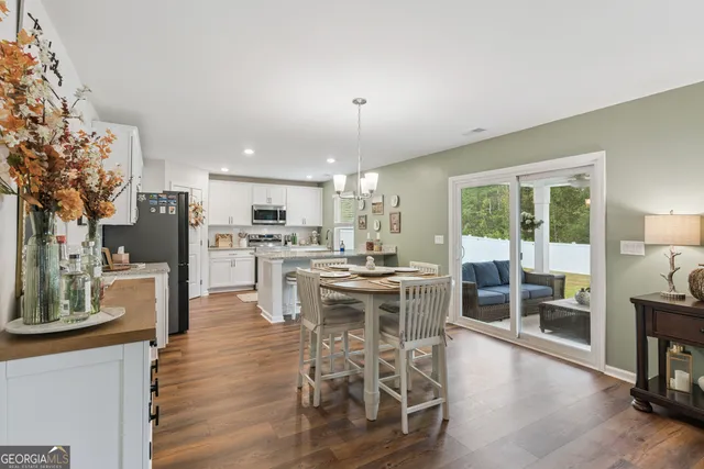 a kitchen with stainless steel appliances kitchen island granite countertop a table chairs refrigerator and sink