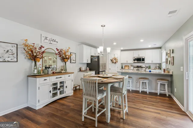 a open kitchen with stainless steel appliances granite countertop a stove top oven a sink dishwasher a dining table and chairs with wooden floor
