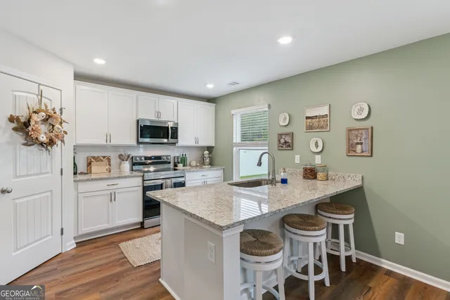 a kitchen with stainless steel appliances granite countertop a refrigerator a stove a sink dishwasher a dining table and chairs with wooden floor