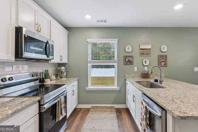 a kitchen with stainless steel appliances granite countertop a sink refrigerator and cabinets