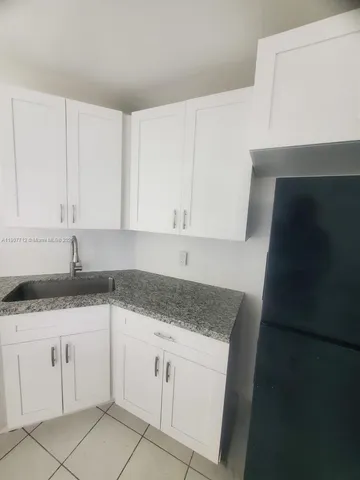 a kitchen with granite countertop white cabinets and a sink
