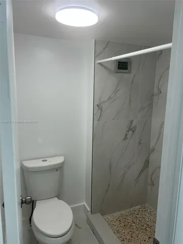 a white toilet sitting next to a shower